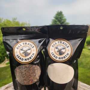 All Trails Lead North cultivated wild rice and wild rice pancake mix 16 oz pouches displayed on wood railing with green nature background